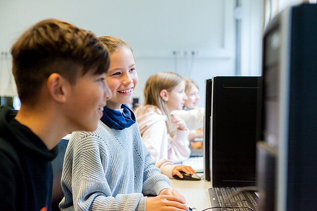 SchülerInnen arbeiten zusammen vor dem PC