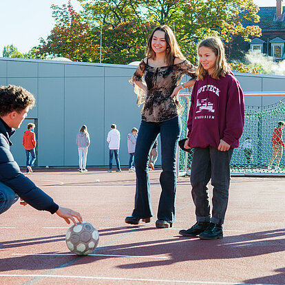 Älterer Schüler erklärt Schülerin Fußballtechnik